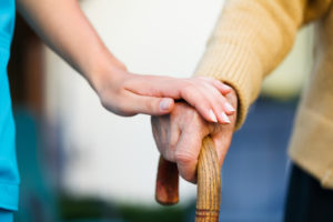 Doctor holding a senior patiens 's hand on a walking stick - special medical care concept for Alzheimer 's syndrome.